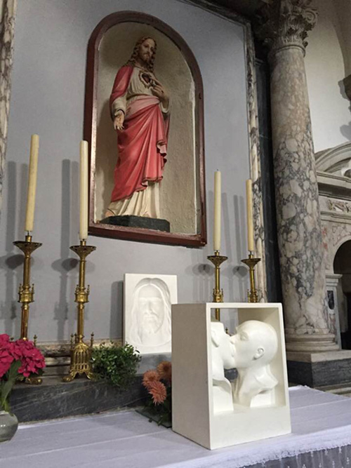 homosexuals kissing sculpture at altar